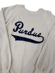 An off-white long-sleeve raglan sweatshirt featuring a navy blue 'Purdue' script graphic with a navy plaid accent on the letter 'U', shown against a plain white background.
