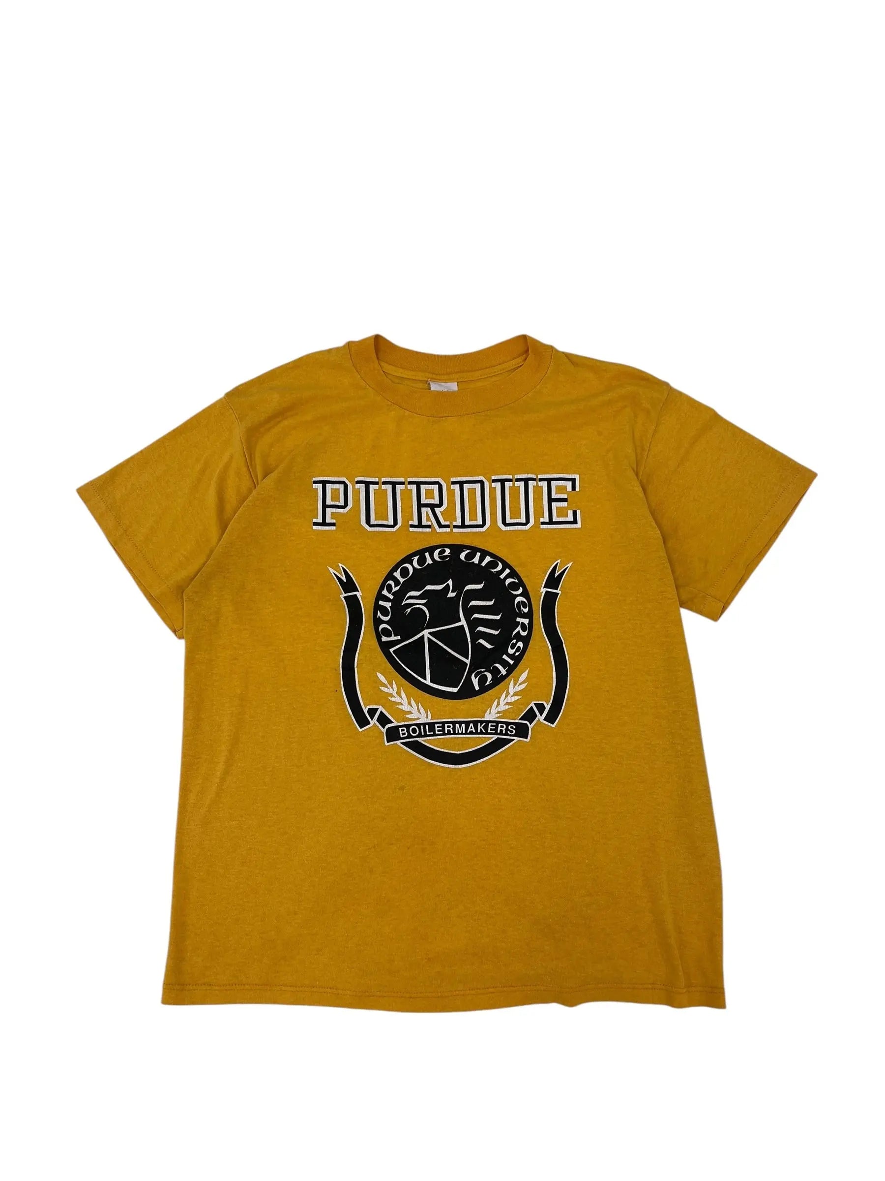 A mustard yellow t-shirt laid flat on a white background, featuring a black and white Purdue University crest graphic and the word 'PURDUE' printed vertically on the front.