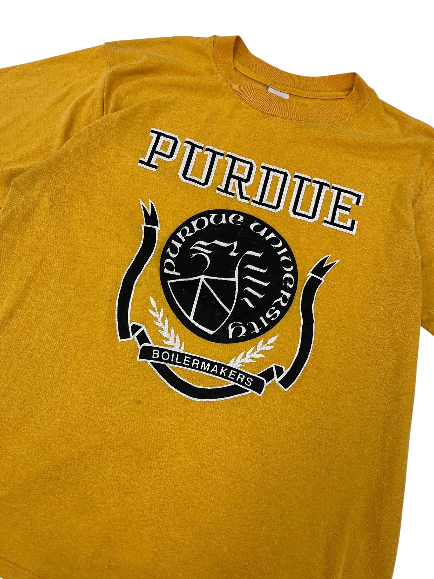 Close-up of a mustard yellow t-shirt featuring a black and white Purdue Boilers graphic on the front.