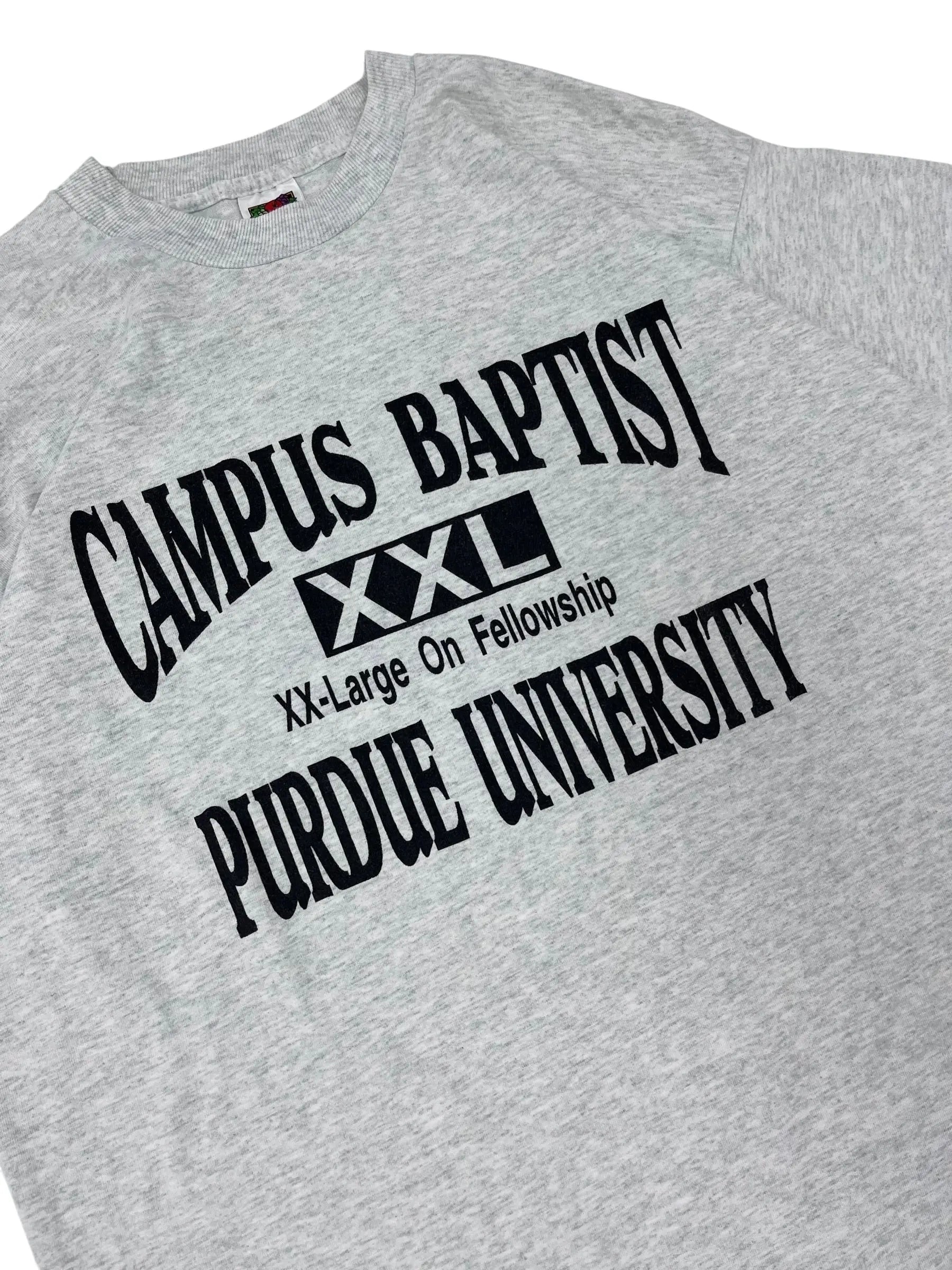 Close-up of a heather gray t-shirt featuring a black printed graphic for Purdue University Campus Baptist with a small red, white, and blue flag tag visible on the inside neck.