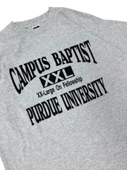 Close-up of a heather gray t-shirt featuring a black printed graphic for Purdue University Campus Baptist with a small red, white, and blue flag tag visible on the inside neck.